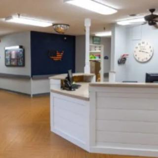 A well-lit reception area with a front desk and a clock on the wall.
