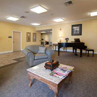 A cozy lobby area featuring a piano, comfortable seating, and a coffee table with magazines.