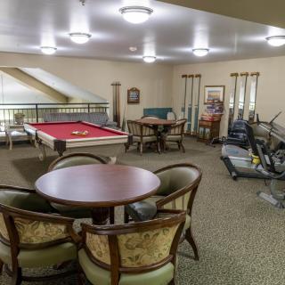 A recreation room featuring a pool table, exercise equipment, and a seating area.
