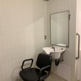 A minimalist room featuring a chair, sink, and mirror.