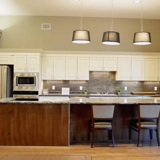 Modern kitchen with sleek design featuring stainless steel appliances and a spacious countertop with bar stools.