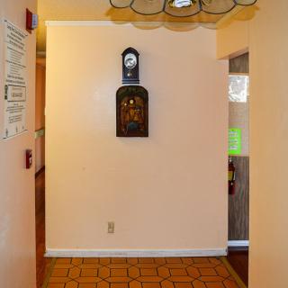 A hallway with a wall clock and tiled floor.