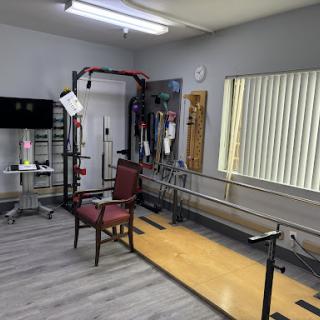 A well-equipped rehabilitation therapy room featuring exercise equipment and assistance bars.