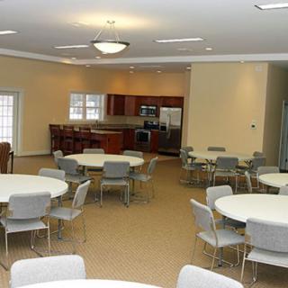 A community center with round tables, chairs, and a kitchen area.
