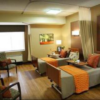 A well-equipped hospital room with comfortable seating and warm decor.