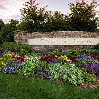 A beautifully landscaped garden with a variety of colorful flowers in front of a stone wall sign.