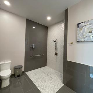 A contemporary bathroom featuring a spacious shower area and sleek gray tiles.
