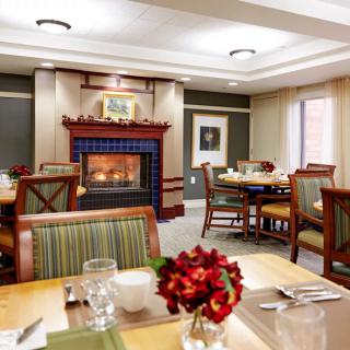 A cozy dining room with a fireplace and elegantly arranged tables and chairs.