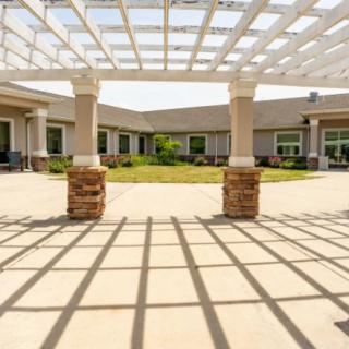 A sunlit courtyard with a pergola providing shade over the patio.