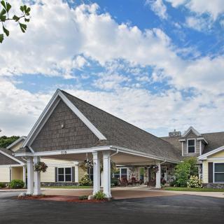 A residential building with a pitched roof and covered entrance under a partly cloudy sky.