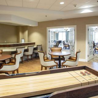A modern community seating area featuring tables, chairs, and a shuffleboard table.
