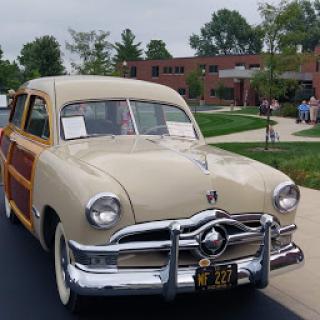A beautifully restored vintage Ford station wagon with classic wood paneling on display at a car show.