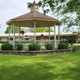 A charming gazebo surrounded by lush greenery and a well-manicured lawn.