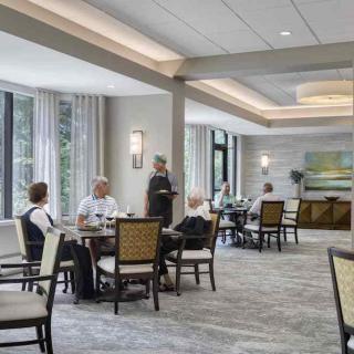 A spacious dining area with seniors enjoying a meal at various tables.