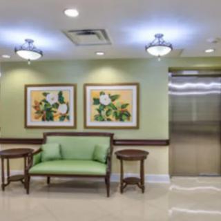 A well-lit lobby area featuring a green loveseat, decorative artwork, and an elevator.