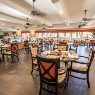 A cozy restaurant dining area with elegantly arranged tables and chairs, featuring warm lighting and stylish decor.