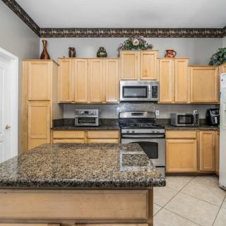 Modern kitchen with granite countertops, wood cabinets, and stainless steel appliances.