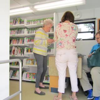 A group of people inside a mobile library browsing books.