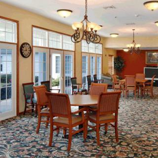 A spacious dining room with elegant chandeliers, large windows, and wooden furniture.