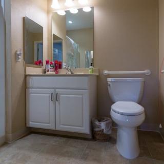 A well-lit bathroom with a sink, mirror, and toilet.