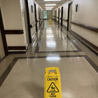 A hallway in a hospital with a caution sign warning of a slippery floor.