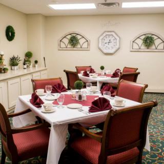 A neatly arranged dining room with red chairs and tables set for a meal.