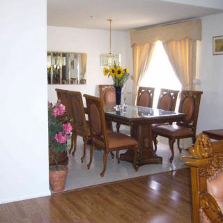 A cozy dining room with a wooden table and chairs, decorated with sunflowers in a vase and indoor plants.