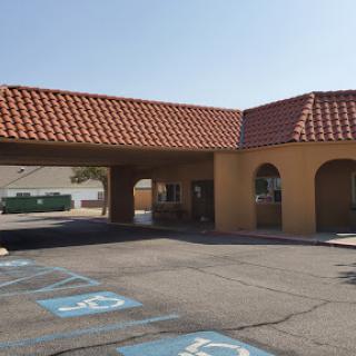 The entrance of a commercial building featuring a tiled roof and designated parking spaces.