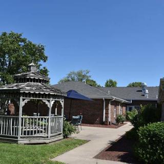 A scenic view of a gazebo next to a brick building under a clear blue sky.