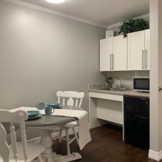 A small dining area with a table set, adjacent to a compact kitchen space equipped with cabinets, a microwave, and a mini fridge.