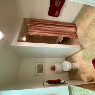 A clean and organized bathroom with a shower, toilet, and neatly arranged towels.
