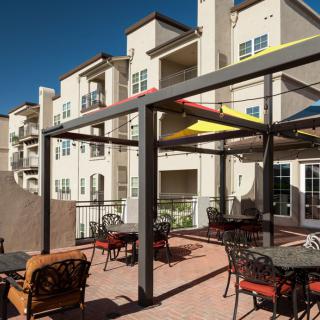 Modern apartment complex with a stylish outdoor patio area featuring seating and a pergola.