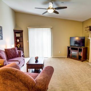 A cozy living room featuring a plush sofa, TV, and bookshelf with soft lighting and neutral decor.