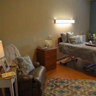 A cozy and well-furnished hospital room with a bed and seating area.