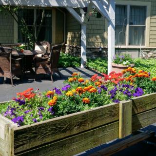 A beautiful garden with a raised flower bed and outdoor seating on a patio.