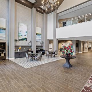 A spacious and elegantly designed lobby featuring a high ceiling, chandelier, and modern furniture.