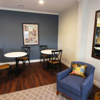 A cozy seating area with round tables and a blue armchair against a stylish blue accent wall.