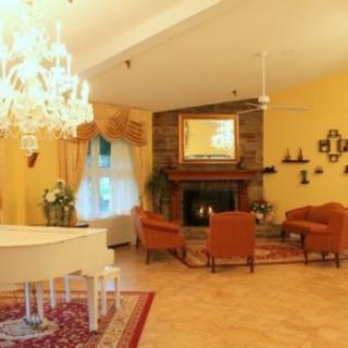 A warm and inviting living room featuring a grand piano, elegant chandelier, and cozy seating area.