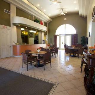 A spacious restaurant lobby with tables and chairs, featuring a high ceiling and large arch window.