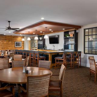 A cozy restaurant interior with wooden furniture and a bar area.
