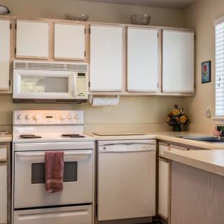 A cozy kitchen featuring a range of white appliances and cabinetry.