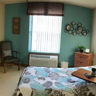 A cozy bedroom with teal accent wall and floral bedspread.