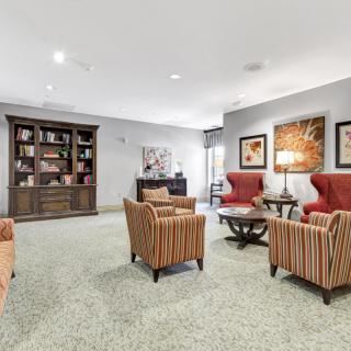 A cozy living room with comfortable seating, a bookshelf, and warm lighting.