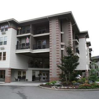 A modern residential apartment building with multiple balconies and landscaped surroundings.