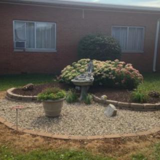 A small landscaped garden with a variety of plants and flowers surrounded by gravel.