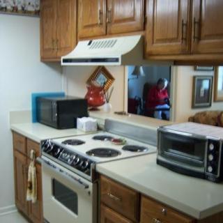 A cozy kitchen with wooden cabinets and various appliances, including a stove, microwave, and toaster oven.