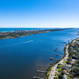 A stunning aerial view showcasing a tranquil river bordered by residential areas and a vibrant city skyline in the distance.