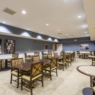 A well-lit dining room with neatly arranged tables and chairs, featuring artwork on the walls.