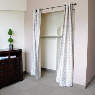 A minimalist bedroom with an open closet featuring curtains as a door alternative.