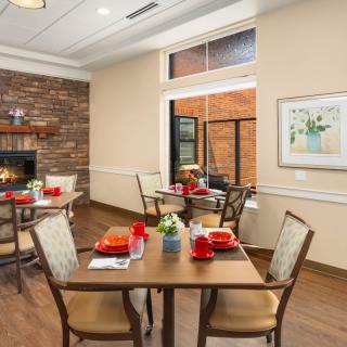 A cozy dining room with neatly set tables and a fireplace.
